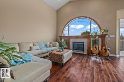 Living area featuring vaulted ceilings, wood-finish flooring, and a fireplace with a wood mantle - 