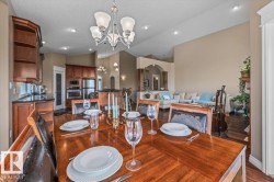 Open-concept dining area featuring wood-finish flooring, a contemporary chandelier, recessed lighting, and warm neutral wall tones - 