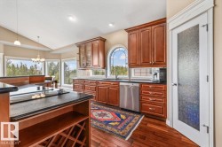 Kitchen featuring wood-finish flooring, custom wood cabinetry, and dark countertops - 