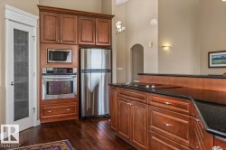 Gourmet kitchen featuring stainless steel appliances, rich wood cabinetry, dark countertops, a built-in oven, and a cooktop on the island - 