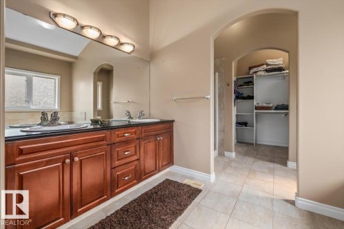 Dual vanity featuring wood cabinetry, dark countertops, and chrome fixtures - 215 Westerra Point(E), Stony Plain, AB 
