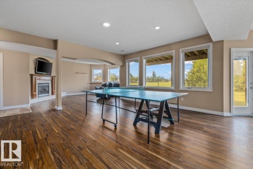 Spacious lower-level area featuring wood-finish flooring, recessed lighting, and large windows providing ample natural light - 215 Westerra Point(E), Stony Plain, AB 