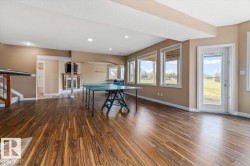 Spacious lower level featuring wood-finish flooring, recessed lighting, and a fireplace with a wood mantle - 