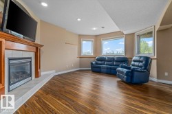 Spacious room featuring wood-finish flooring, a built-in fireplace with a tile surround and wood mantel, recessed lighting, and multiple windows - 