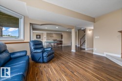 Spacious recreation room featuring wood-finish flooring, a window providing natural light, and a fireplace hearth - 