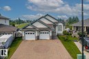 Split-level residence featuring a two-car garage with stone detailing, a patterned paver driveway, and a manicured front lawn - 215 Westerra Point(E), Stony Plain, AB 