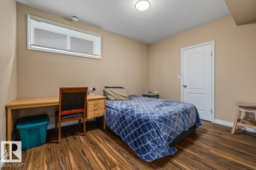 Room featuring wood-finish flooring, a contemporary flush-mount ceiling light, and a white interior door - 215 Westerra Point(E), Stony Plain, AB 