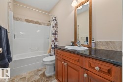 Bathroom featuring a wood-finish vanity with a dark countertop and an undermount sink - 