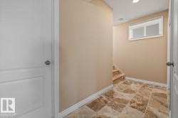 Hallway featuring large format tiled flooring, a window with horizontal blinds, and a staircase with coordinated tile risers - 