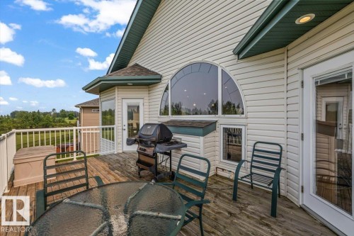 Spacious outdoor wood-finish deck featuring a white railing and multiple exterior doors - 215 Westerra Point(E), Stony Plain, AB 