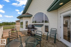Spacious outdoor wood-finish deck featuring a white railing and multiple exterior doors - 