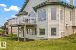 Exterior featuring a raised deck with white railing, a ground-level patio door, and multiple windows across two levels - 
