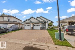 Ranch-style exterior with a two-car garage, stone façade accents, and a paved driveway - 