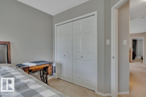 White bi-fold closet doors with brushed nickel hardware, neutral carpet flooring, and light gray wall paint - 6042 214 Street, Edmonton, AB - Indoor Photo Showing Bedroom