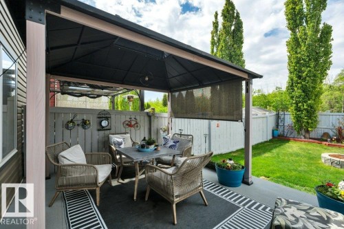 Covered patio with durable surface flooring, privacy screen, and permanent overhead structure - 6042 214 Street, Edmonton, AB - Outdoor With Deck Patio Veranda