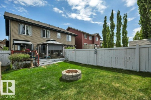Expansive rear yard featuring a stone fire pit, wood privacy fencing, and a deck - 6042 214 Street, Edmonton, AB - Outdoor