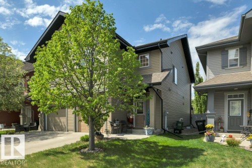 Two-story property with an attached garage, a paved driveway, a covered front entry, and a manicured front lawn - 6042 214 Street, Edmonton, AB - Outdoor