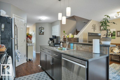 Kitchen island featuring a stainless steel sink with a high-arc faucet, a stainless steel dishwasher, and a corner pantry - 6042 214 Street, Edmonton, AB - Indoor Photo Showing Other Room