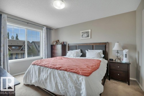 Carpeted bedroom with neutral wall paint and a large window featuring white framing - 6042 214 Street, Edmonton, AB - Indoor Photo Showing Bedroom
