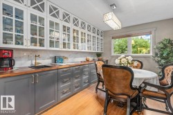 Kitchen and dining area featuring two-tone cabinetry, wood-finish countertops, and a white marble-patterned backsplash - 