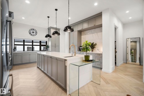 Kitchen featuring light gray cabinetry, a central island with a white countertop, and herringbone-pattern wood-finish flooring - 6115 111 Avenue, Edmonton, AB - Indoor Photo Showing Kitchen With Upgraded Kitchen
