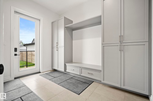 Entryway with light-toned tile flooring, built-in cabinetry, integrated bench seating, and a glass-paneled door - 6115 111 Avenue, Edmonton, AB - Indoor Photo Showing Other Room