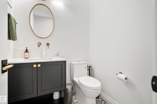 Bathroom featuring a matte black vanity with gold-tone hardware, white countertop, and gold-tone wall-mounted faucet - 6115 111 Avenue, Edmonton, AB - Indoor Photo Showing Bathroom