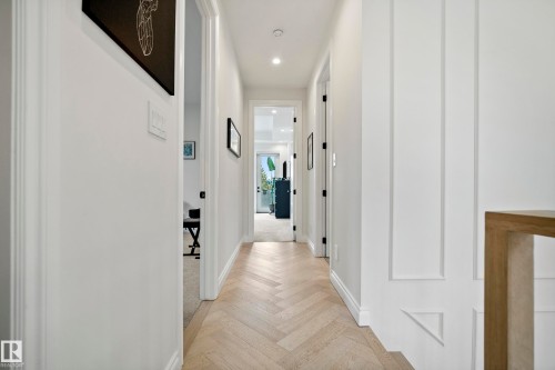 Hallway featuring light wood-finish herringbone flooring, recessed lighting, white baseboards, and board and batten wall detailing - 6115 111 Avenue, Edmonton, AB - Indoor Photo Showing Other Room
