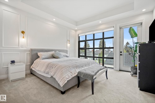 Bedroom featuring a large grid-pane window and a white door with a glass panel - 6115 111 Avenue, Edmonton, AB - Indoor Photo Showing Bedroom
