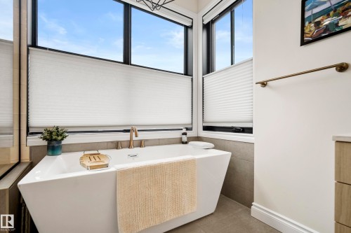 Freestanding soaking tub with brass fixtures, surrounded by large windows featuring privacy blinds - 6115 111 Avenue, Edmonton, AB - Indoor Photo Showing Other Room