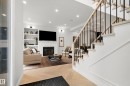 Herringbone wood-finish flooring extending into a living area featuring a fireplace with a white mantel, built-in shelving, and recessed lighting - 6115 111 Avenue, Edmonton, AB  - Indoor Photo Showing Other Room With Fireplace 