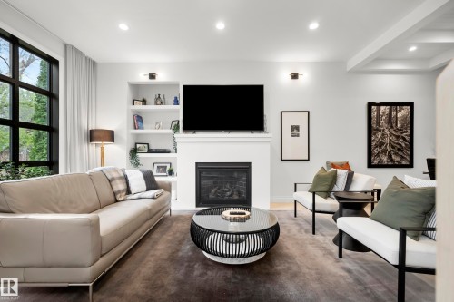 Living area featuring a fireplace with a mantel, built-in shelving, recessed lighting, and large grid-pattern windows - 6115 111 Avenue, Edmonton, AB - Indoor Photo Showing Living Room With Fireplace
