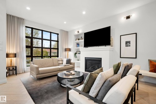 Spacious living area featuring light wood-finish flooring, recessed lighting, and a prominent fireplace with an integrated mantel - 6115 111 Avenue, Edmonton, AB - Indoor Photo Showing Living Room With Fireplace