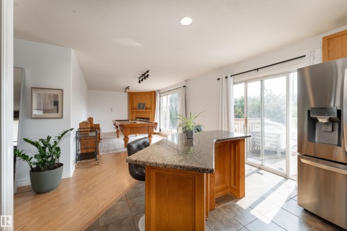 Kitchen island with a granite-style countertop and wood cabinetry - 183 Dechene Road, Edmonton, AB 
