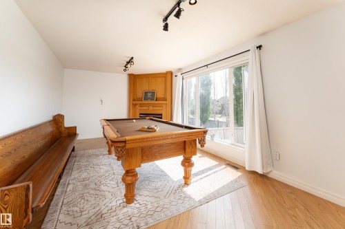 Spacious room featuring wood-finish flooring and a corner-built wooden fireplace - 183 Dechene Road, Edmonton, AB 