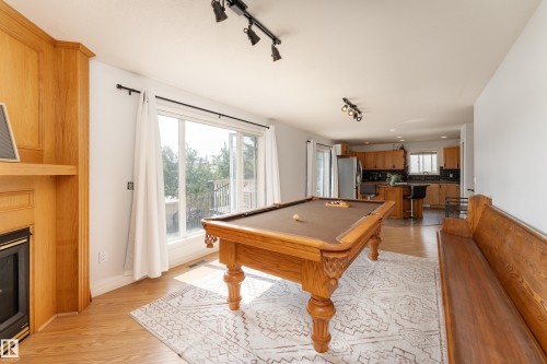 Open-concept living space featuring wood-finish flooring, a built-in fireplace with custom wood surround, and sliding glass doors - 183 Dechene Road, Edmonton, AB 