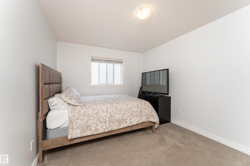 Bedroom featuring white walls, neutral carpet, a window with horizontal blinds, and a flush-mount ceiling light fixture - 183 Dechene Road, Edmonton, AB 
