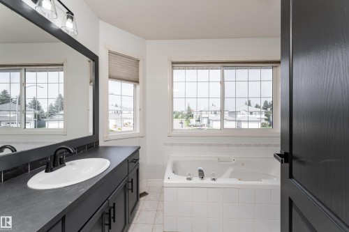 Deep soaking tub with white tile surround and multiple windows with grids - 183 Dechene Road, Edmonton, AB 