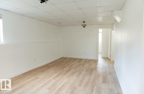 Expansive room featuring light wood-finish flooring, white walls, and a drop ceiling - 183 Dechene Road, Edmonton, AB 