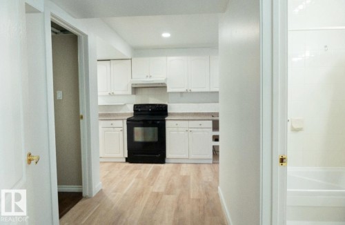 Kitchen with white cabinetry, light-toned countertops, and a black range - 183 Dechene Road, Edmonton, AB 