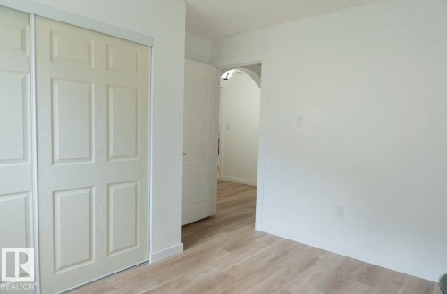 Light wood-finish flooring extending into an arched doorway - 183 Dechene Road, Edmonton, AB 