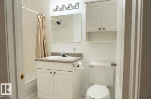 Bathroom featuring a white vanity with a light-colored countertop, an integrated sink, and an overhead mirror with task lighting - 183 Dechene Road, Edmonton, AB 