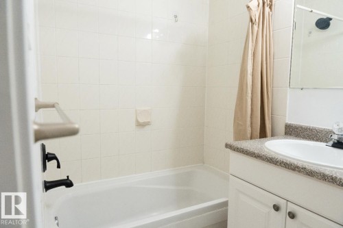 White subway tile surround with integrated bathtub and black fixtures - 183 Dechene Road, Edmonton, AB 