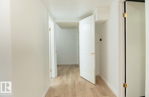 Hallway featuring light wood-finish flooring, white walls, and bright white trim - 183 Dechene Road, Edmonton, AB 