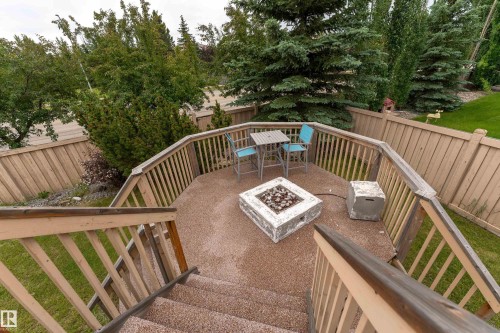 Spacious backyard deck featuring a textured aggregate surface, wood railings, and privacy fencing - 183 Dechene Road, Edmonton, AB 