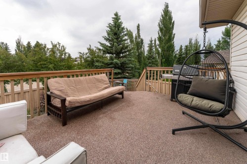 Spacious outdoor deck featuring a textured aggregate surface, natural wood railing, and a slatted privacy fence - 183 Dechene Road, Edmonton, AB 
