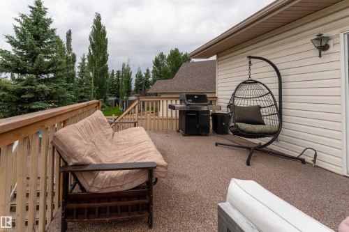 Spacious outdoor deck featuring light wood railings, textured flooring, and light-colored horizontal siding - 183 Dechene Road, Edmonton, AB 