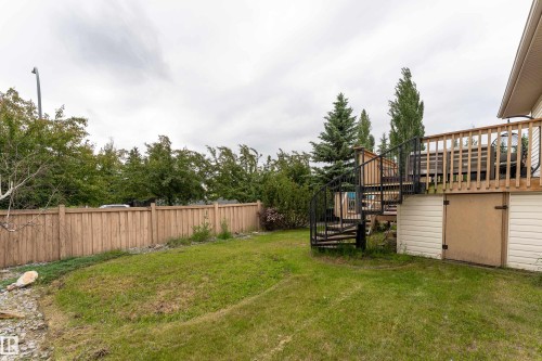 Expansive backyard featuring a wood privacy fence and mature trees - 183 Dechene Road, Edmonton, AB 