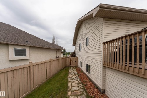 Exterior featuring a side deck with wood railings, light-colored siding, and a stone-paver walkway - 183 Dechene Road, Edmonton, AB 