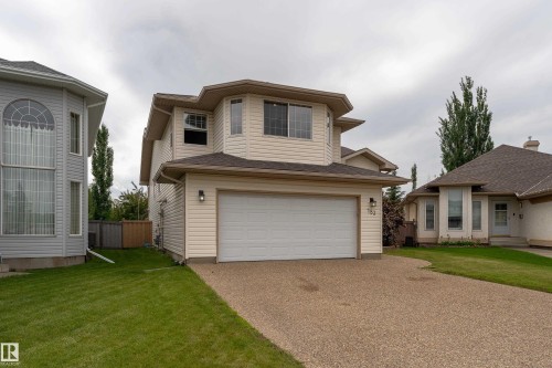 Two-story residence featuring light-colored siding, a two-car garage, and a gravel driveway - 183 Dechene Road, Edmonton, AB 